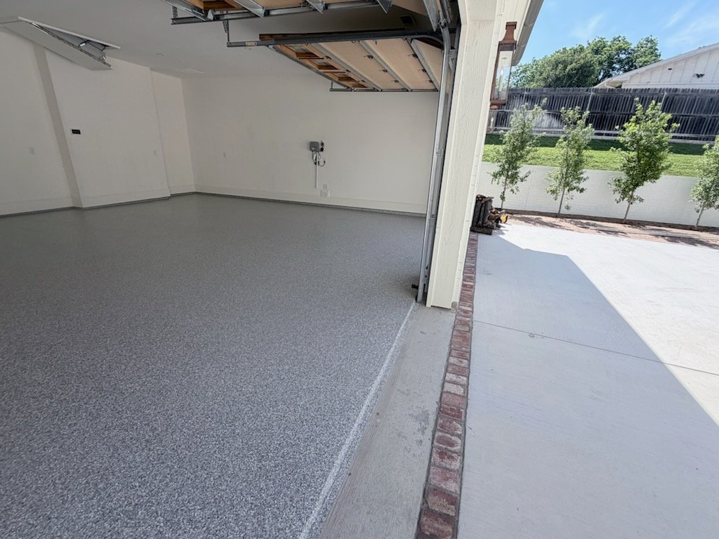 Installer applying epoxy flooring coating inside a Fort Worth - TX garage with careful edge work