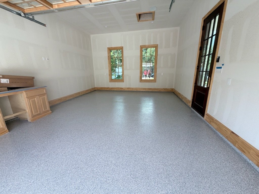 Installer applying epoxy flooring coating inside a Fort Worth - TX garage with careful edge work
