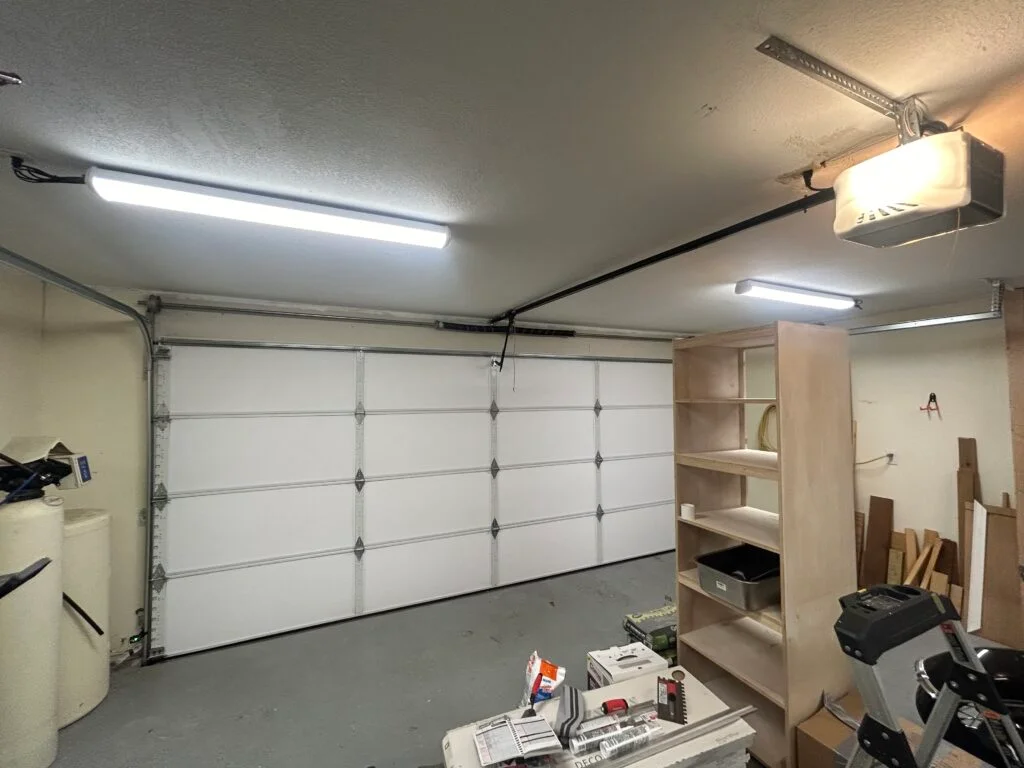 Technician performing garage door replacement adjustments at a Fort Worth - TX home with alignment tools, Technician performing garage door repair on a spring system inside a Hudson Oaks - TX home garage